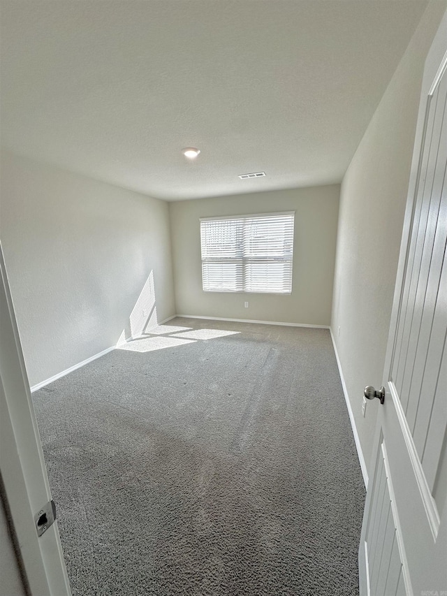 carpeted empty room with visible vents and baseboards