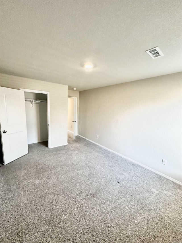 unfurnished bedroom with a closet, visible vents, a textured ceiling, and carpet flooring