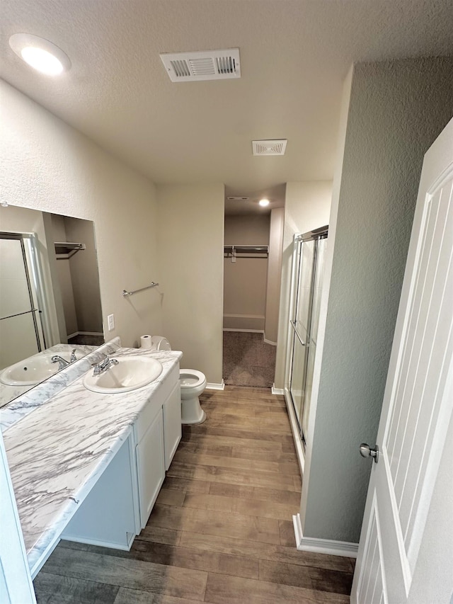 bathroom featuring visible vents, a shower stall, vanity, and wood finished floors