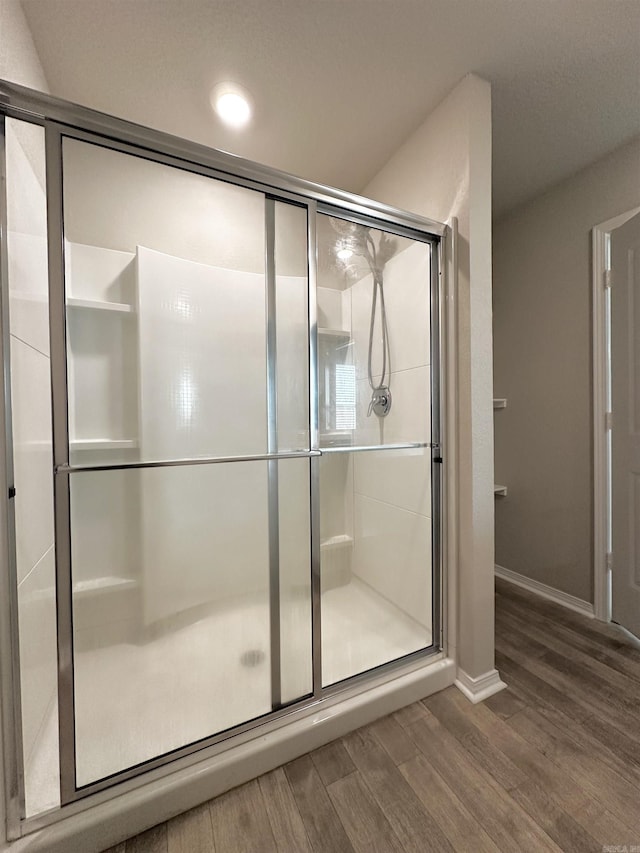 bathroom with a stall shower, baseboards, and wood finished floors