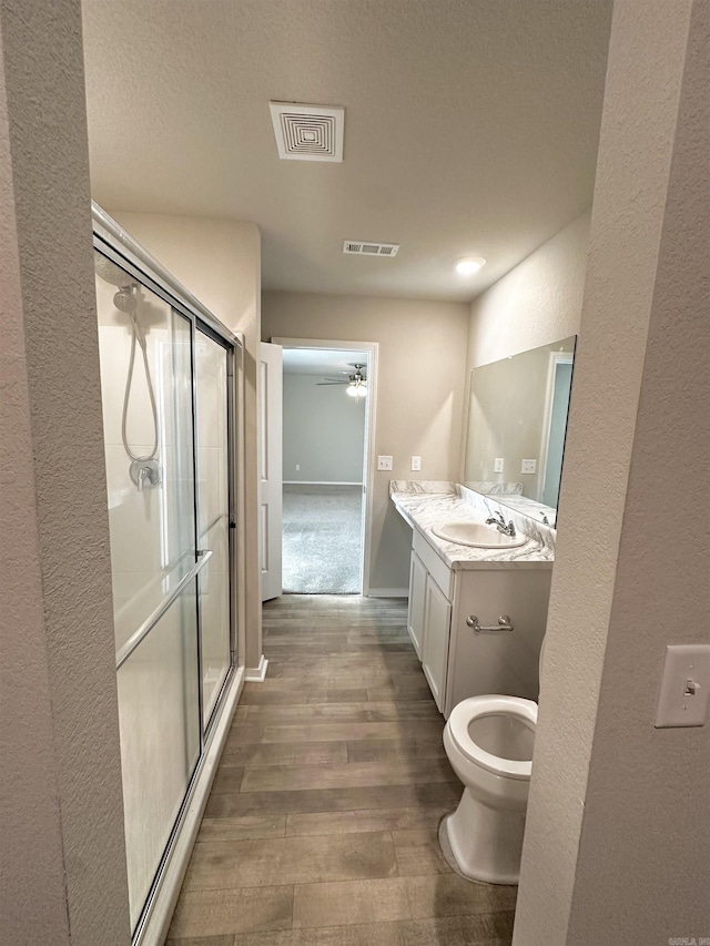 bathroom with vanity, a stall shower, wood finished floors, and visible vents