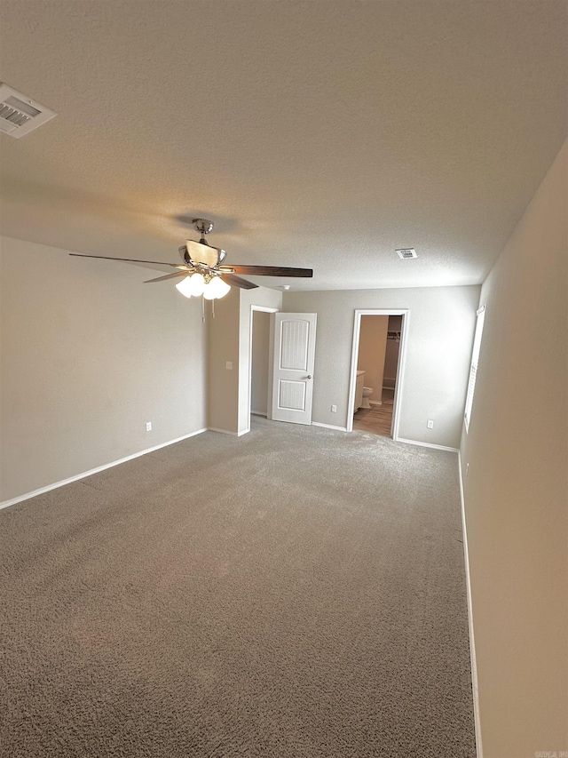 spare room featuring a textured ceiling, ceiling fan, carpet floors, visible vents, and baseboards