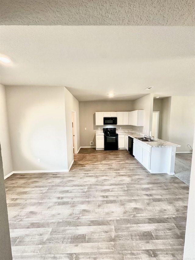 kitchen featuring light wood-style flooring, baseboards, open floor plan, white cabinets, and black appliances