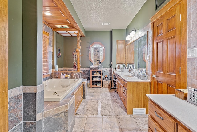 full bath featuring a whirlpool tub, visible vents, a textured ceiling, and vanity