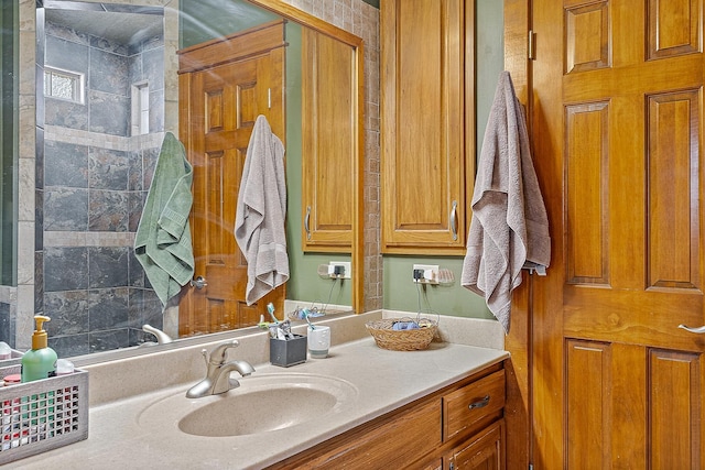 bathroom with tiled shower and vanity