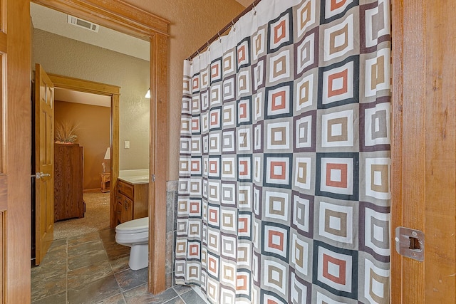 full bathroom featuring toilet, visible vents, stone finish floor, and a shower with shower curtain