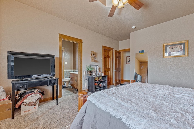 carpeted bedroom with a ceiling fan, a textured wall, connected bathroom, and a textured ceiling