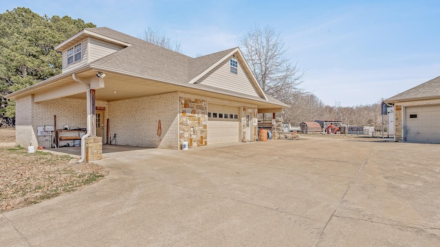 view of home's exterior with a garage, driveway, roof with shingles, and brick siding