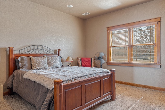 bedroom with light carpet, a textured wall, visible vents, and baseboards