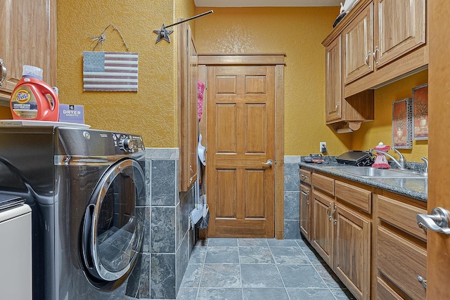 laundry room with washing machine and dryer, stone finish floor, cabinet space, and a sink