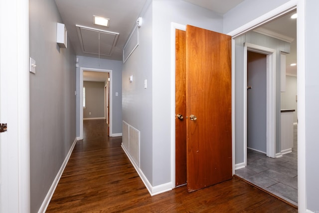 hall with attic access, visible vents, dark wood finished floors, and baseboards