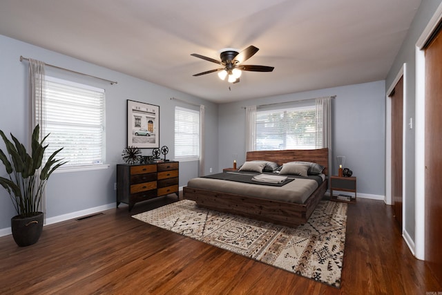 bedroom featuring baseboards, multiple windows, visible vents, and dark wood finished floors