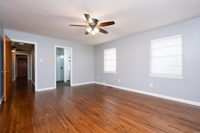 empty room featuring a ceiling fan, visible vents, baseboards, and dark wood-type flooring