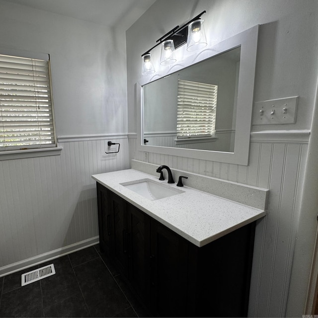 bathroom with a wainscoted wall, vanity, visible vents, and tile patterned floors