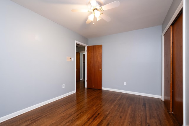 unfurnished bedroom with a ceiling fan, a closet, baseboards, and dark wood-style flooring