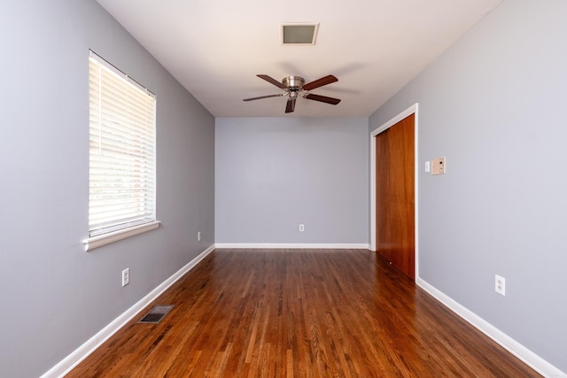 unfurnished room with a ceiling fan, baseboards, visible vents, and dark wood-style flooring