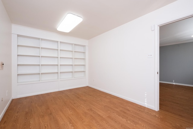 spare room featuring baseboards and wood finished floors