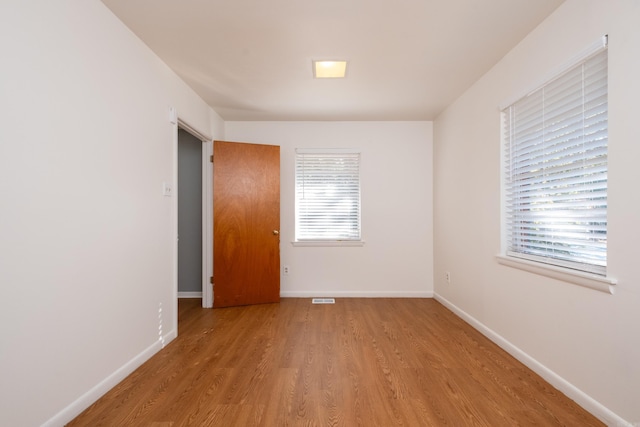 spare room with visible vents, baseboards, and wood finished floors