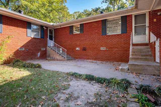 view of exterior entry with crawl space and brick siding