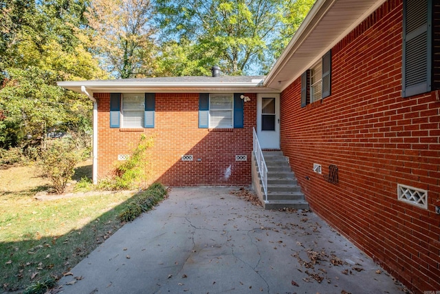 doorway to property with crawl space and brick siding