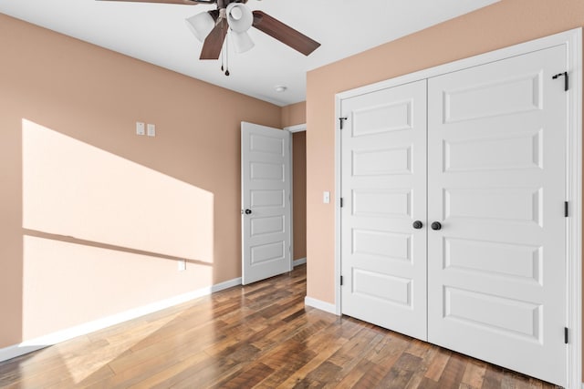 unfurnished bedroom featuring dark wood-style floors, a closet, a ceiling fan, and baseboards