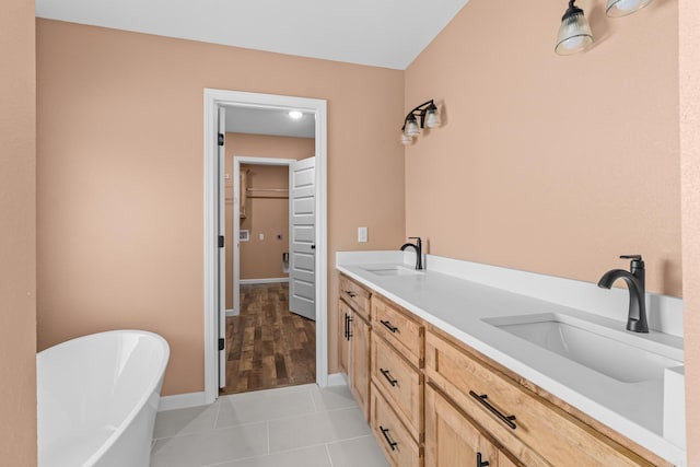 bathroom with tile patterned flooring, a soaking tub, a sink, and a spacious closet