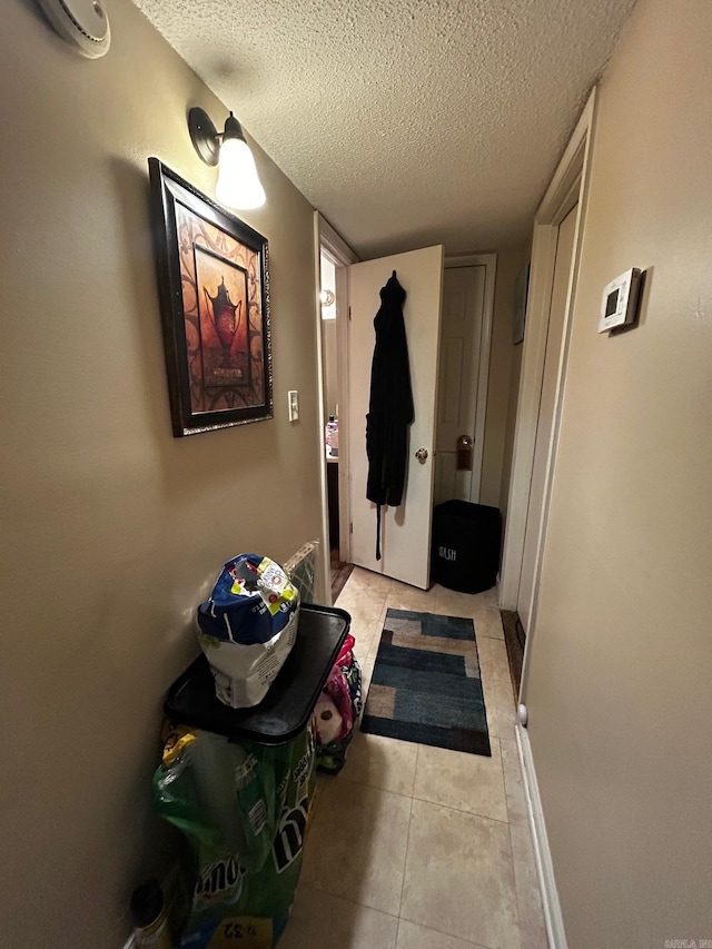 interior space with light tile patterned floors, baseboards, a textured ceiling, and a wall mounted AC