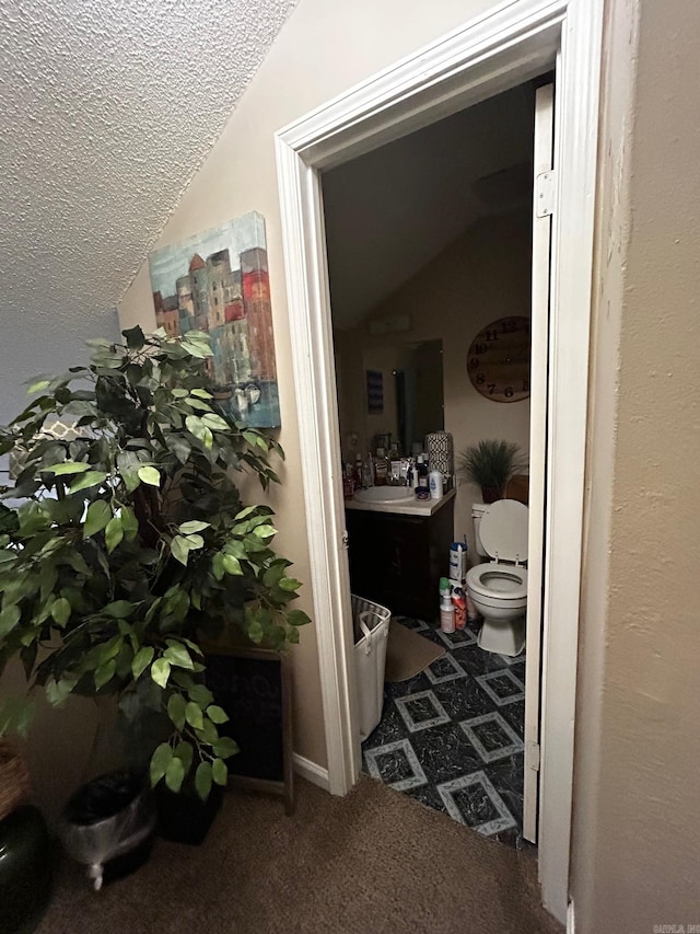 bathroom with vaulted ceiling, vanity, and toilet