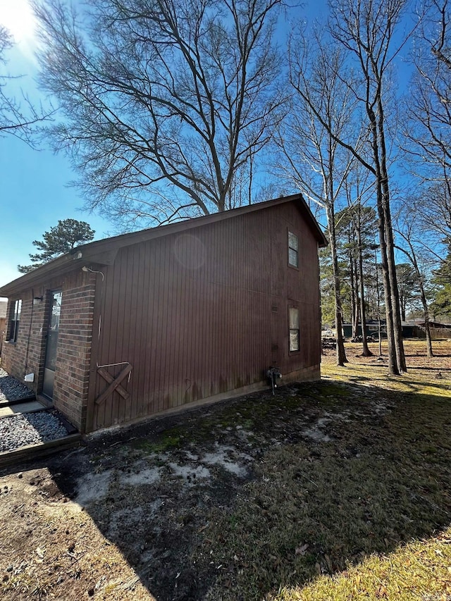 view of property exterior featuring brick siding and an outdoor structure