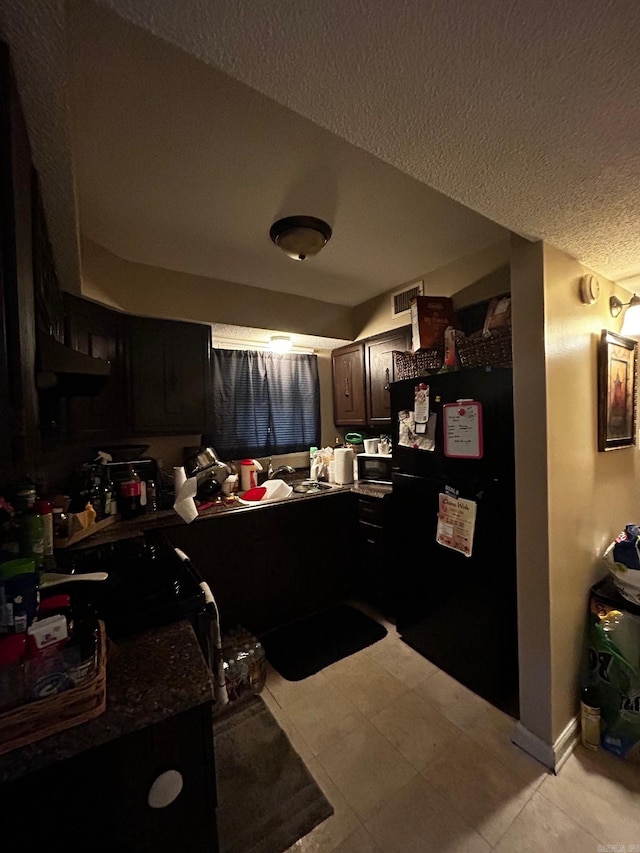 kitchen with light tile patterned floors, visible vents, dark countertops, a textured ceiling, and black appliances