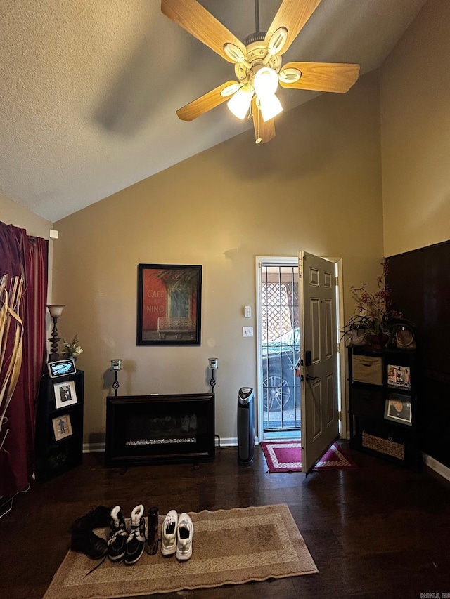 living room featuring a fireplace, vaulted ceiling, a textured ceiling, and ceiling fan