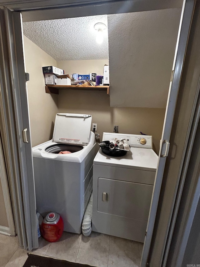 laundry area with light tile patterned floors, laundry area, separate washer and dryer, and a textured ceiling