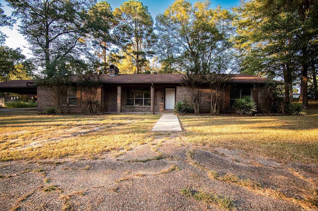 single story home with brick siding, a chimney, and a front lawn