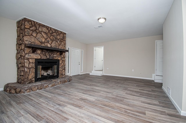 414 W Padgett Rd, El Dorado, AR 71730 - unfurnished living room with a stone fireplace, wood finished floors, visible vents, and baseboards
