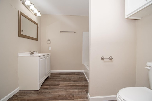 full bathroom with toilet, baseboards, wood finished floors, and vanity