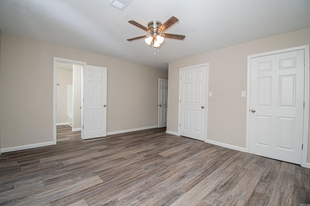 unfurnished bedroom with a ceiling fan, wood finished floors, visible vents, and baseboards