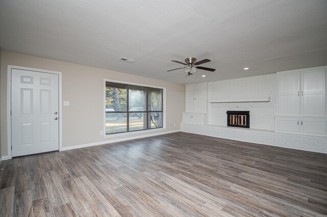 414 W Padgett Rd, El Dorado, AR 71730 - unfurnished living room with baseboards, visible vents, wood finished floors, a textured ceiling, and a brick fireplace