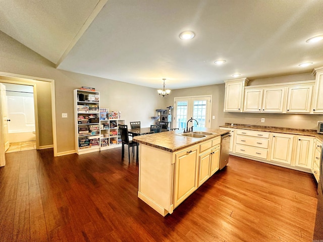 kitchen with stainless steel dishwasher, a center island with sink, a sink, and dark wood finished floors