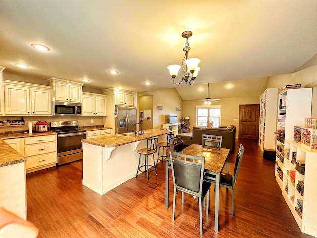 kitchen featuring dark wood-style floors, lofted ceiling, appliances with stainless steel finishes, a sink, and ceiling fan with notable chandelier