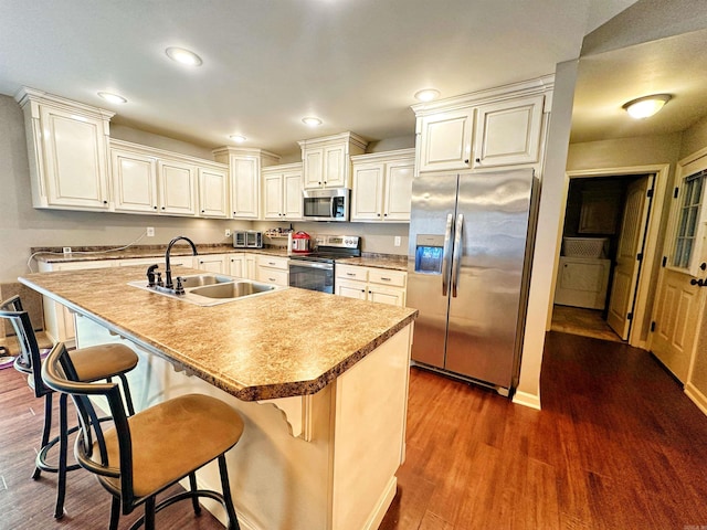 kitchen featuring a breakfast bar, stainless steel appliances, recessed lighting, a sink, and wood finished floors