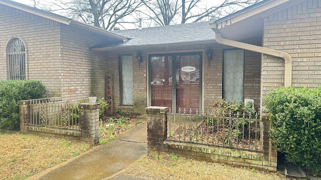 property entrance with a shingled roof and brick siding