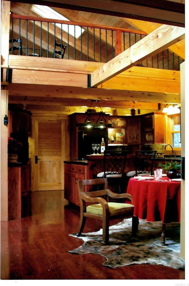 bar with high vaulted ceiling, beam ceiling, wood walls, and wood finished floors