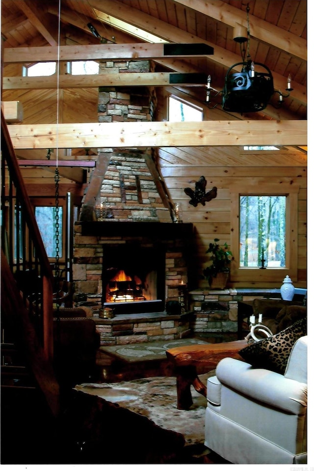 living area with a fireplace, lofted ceiling with beams, wood ceiling, wooden walls, and stairs