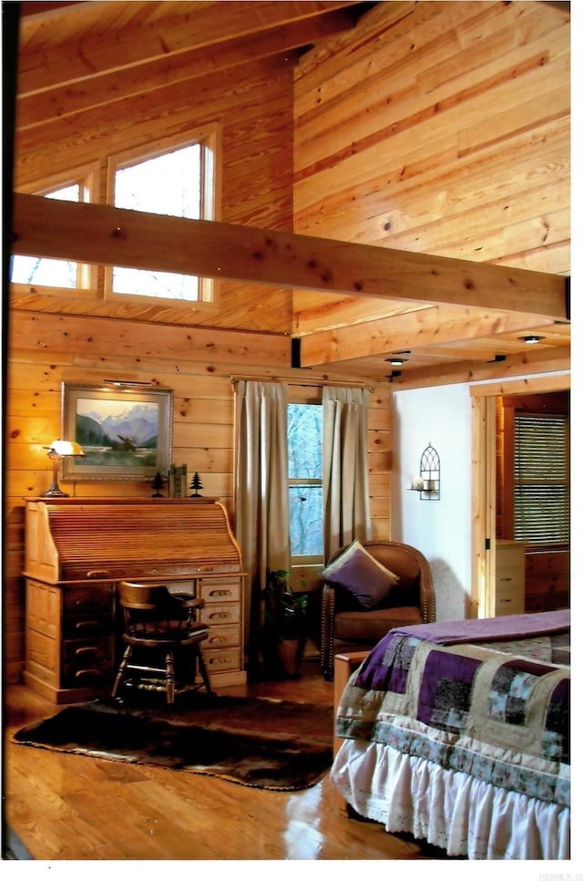 bedroom with a high ceiling, wood finished floors, and wooden walls