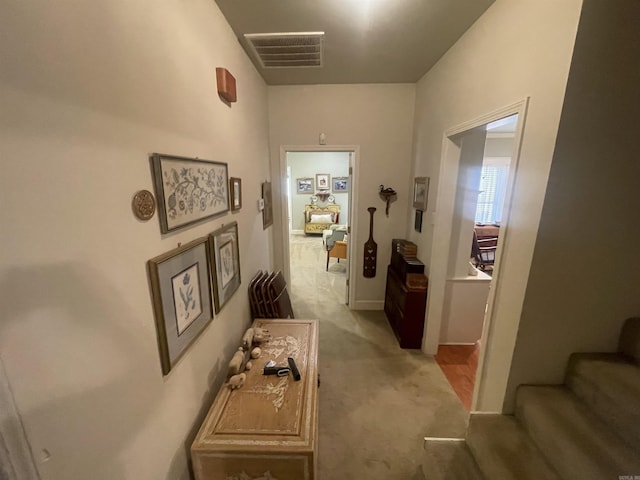 corridor featuring light carpet, stairs, and visible vents