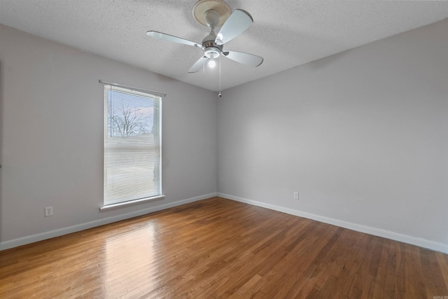 empty room with a textured ceiling, baseboards, and wood finished floors