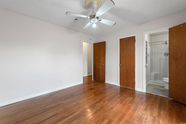 unfurnished bedroom featuring visible vents, a textured ceiling, baseboards, and wood finished floors