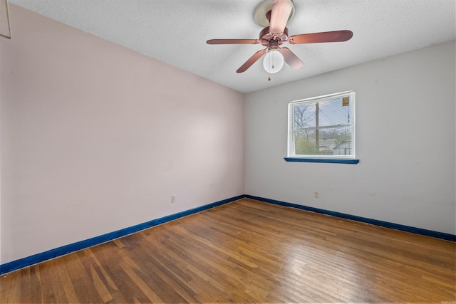 unfurnished room with a textured ceiling, wood finished floors, a ceiling fan, and baseboards