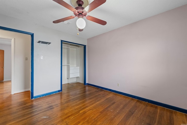 unfurnished bedroom featuring a closet, visible vents, ceiling fan, wood finished floors, and baseboards