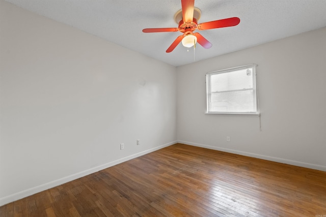 empty room with a textured ceiling, wood-type flooring, a ceiling fan, and baseboards